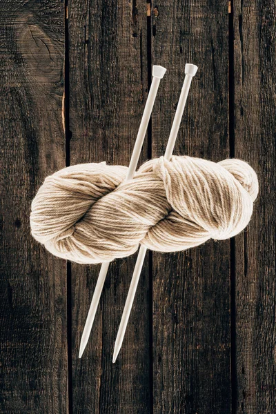 木製の背景に編み針の白いウールのトップ ビュー  — 無料ストックフォト