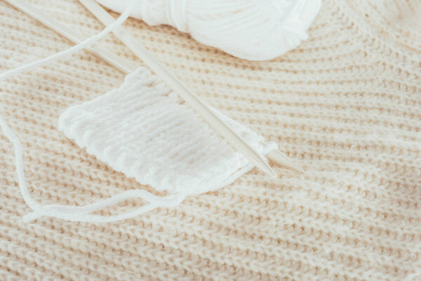 close up of knitting needles with white woolen yarn