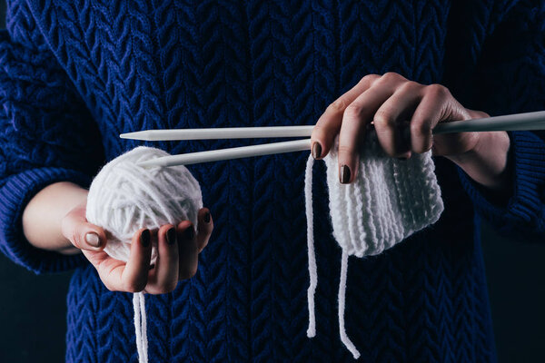 cropped view of female hands with knitting needles and white wool