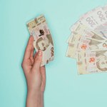 Cropped shot of woman with ukrainian money isolated on turquoise