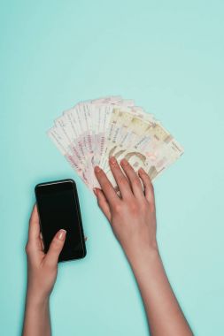 kırpılan nakit ve smartphone üzerinde turkuaz izole kadın ile kadeh