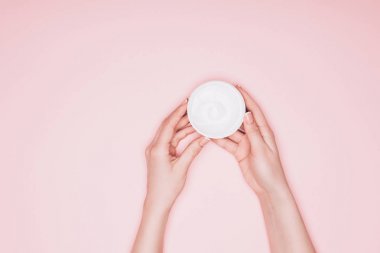 cropped shot of woman holding opened can of moisturizing cream isolated on pink clipart