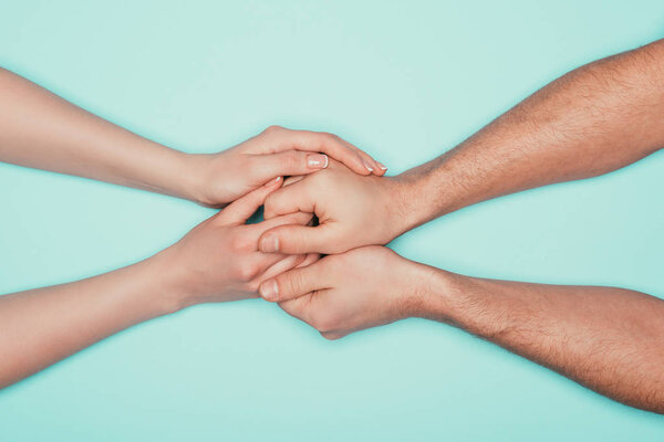 cropped shot of couple holding hands isolated on turquoise