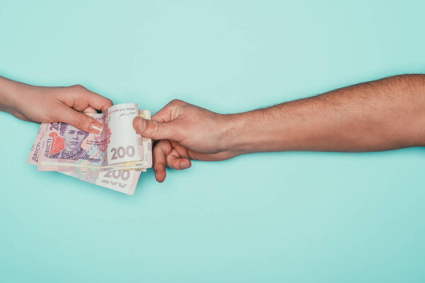 обрезанный снимок мужчины, берущего деньги у женщины, изолированной от бирюзы
