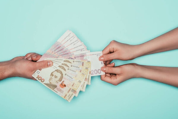 обрезанный снимок женщины, берущей деньги у мужчины, изолированного от бирюзы
