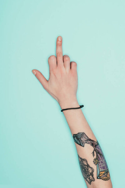cropped shot of woman showing middle finger isolated on turquoise