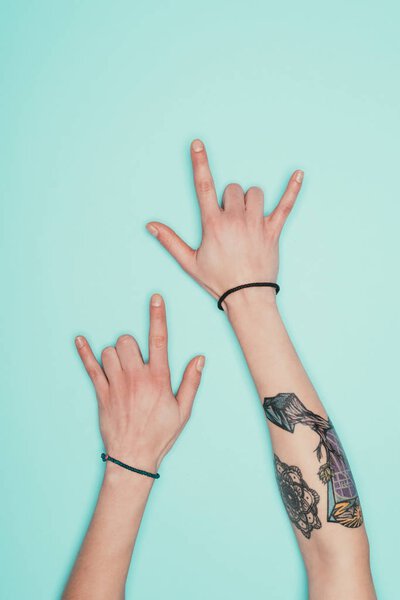 cropped shot of woman showing horns signs isolated on turquoise