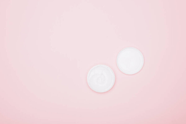 cropped shot of opened jar of cream isolated on pink