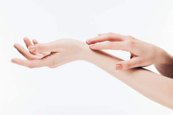 cropped shot of woman applying skincare cream on hands isolated on white
