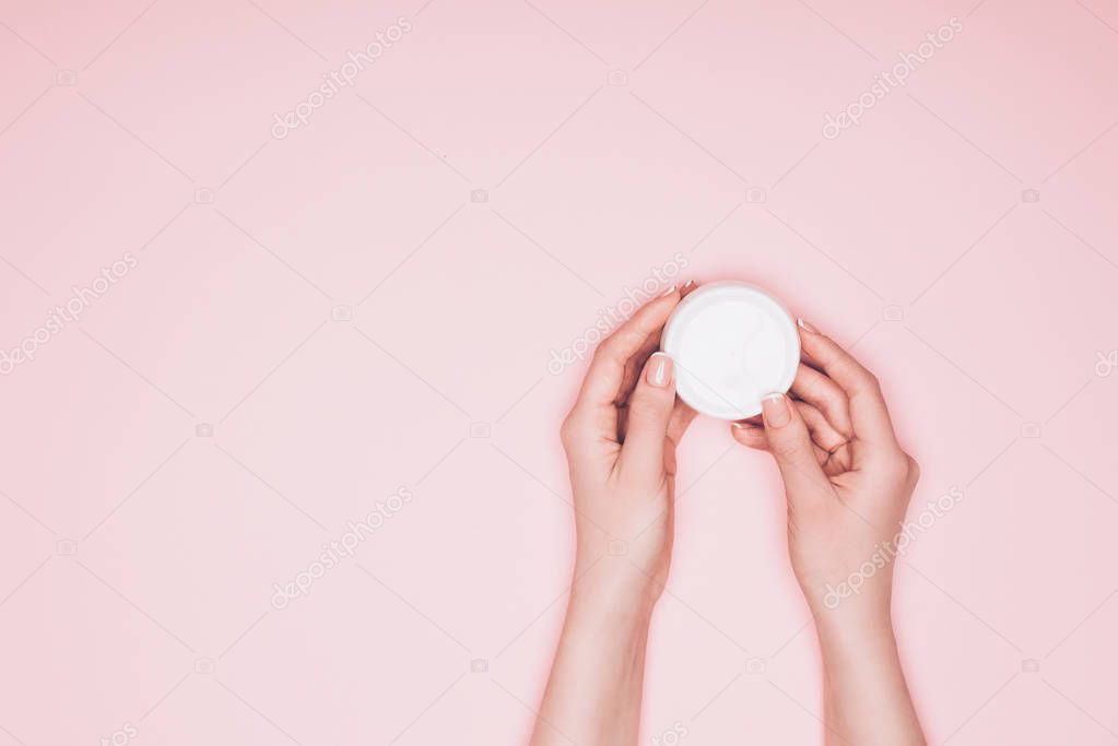 cropped shot of woman holding opened can of moisturizing cream isolated on pink