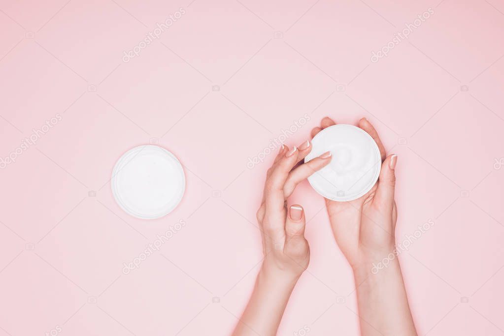 cropped shot of woman taking moisturizing cream from can isolated on pink