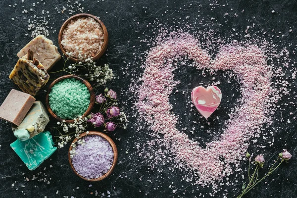 spa Günü Sevgililer günü için siyah mermer yüzeyindeki doğal ev yapımı Sabun ve deniz tuzu kalp şekillerde Üstten Görünüm