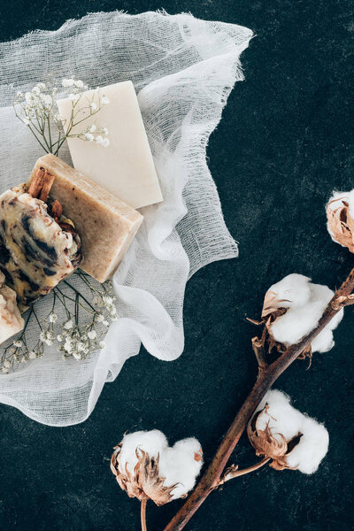 flat lay with natural soap and dried cotton flowers on gauze on marble surface