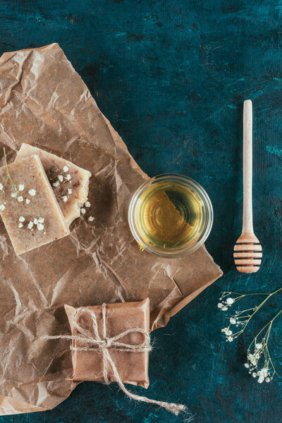 flat lay with natural homemade soap and oil for spa on crumpled paper on green marble surface