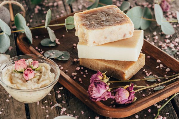 домашнее натуральное мыло, розы и спа соль на деревянной доске
