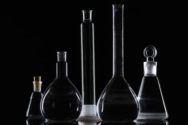 transparent glass flasks with substance in laboratory on black