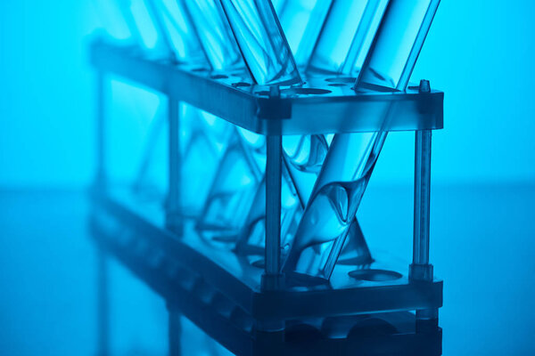 cropped image of glass tubes with liquid on stand in laboratory on blue