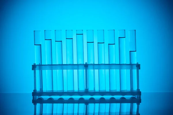 Rangée Tubes Verre Avec Liquide Sur Pied Sur Bleu — Photo