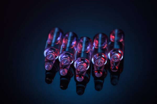 transparent glass ampoules with colored light reflection on table