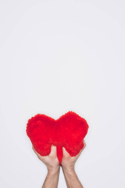 cropped shot of man squeezing soft red heart pillow isolated on white