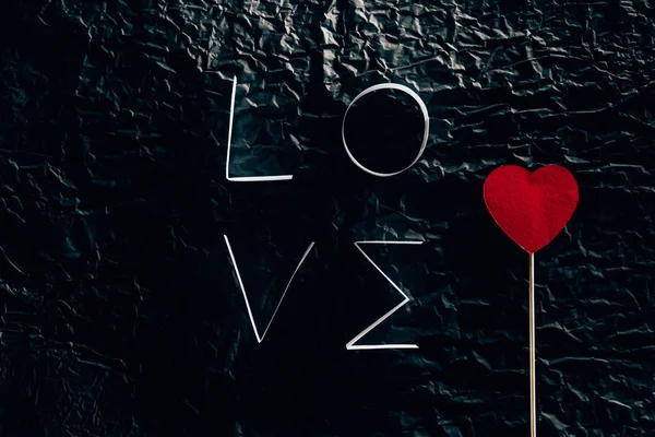 Word LOVE made of paper stripes with heart on stick on black concrete surface — Stock Image Word Love Made Paper Stripes Heart Stick Black Concrete Surface Royalty Free Stock Photos