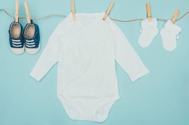 top view of baby clothes drying on rope isolated on blue clipart