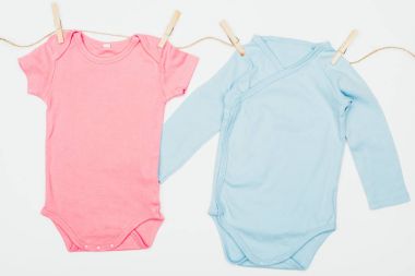 top view of baby bodysuits drying on rope isolated on white clipart