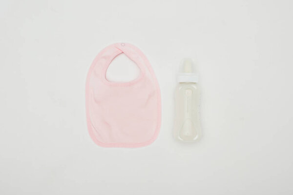 top view of baby bib and bottle of milk isolated on white