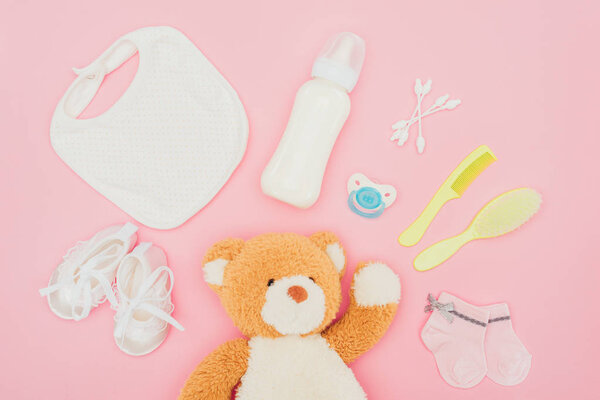 top view of teddy bear and baby equipment isolated on pink