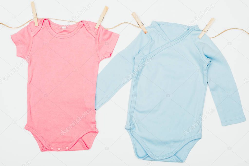 top view of baby bodysuits drying on rope isolated on white
