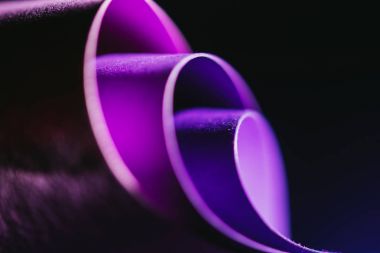 close up view of arcs of purple paper on black