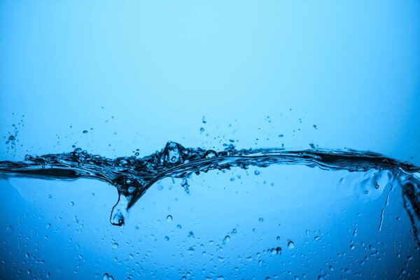 Splashing water with bubbles, isolated on blue
