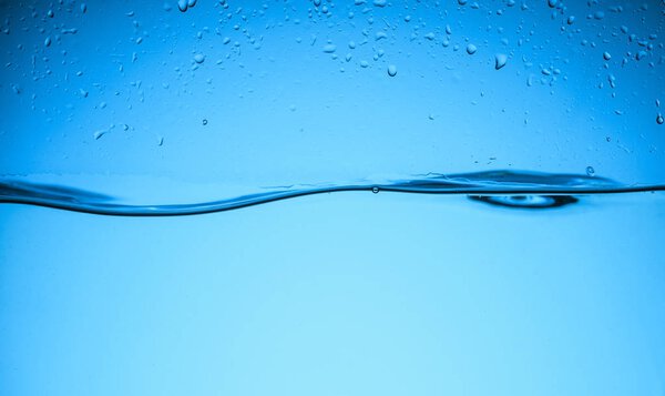 clear flowing water texture with drops, isolated on blue