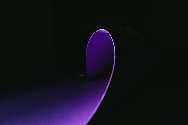 warping purple paper in shape of wave on black
