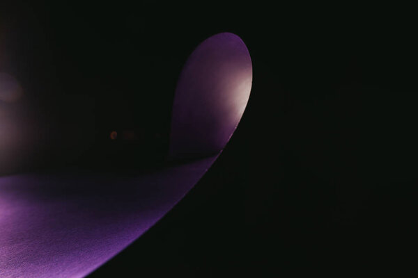 warping purple paper in shape of wave on black