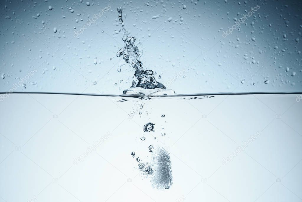 ice cube in water with splash, isolated on white