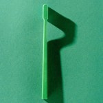 Top view of green toothbrush with shadow, on green