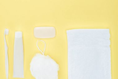 top view of white toothbrush, toothpaste, towel, washcloth and soap, isolated on yellow clipart