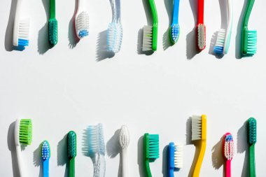 different colorful toothbrushes, on white with copy space clipart