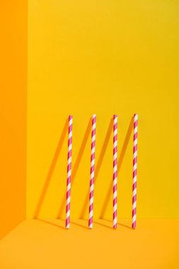 white and red striped straws standing at orange wall clipart