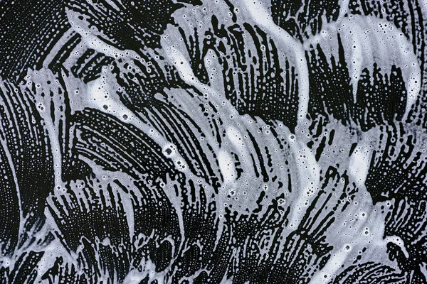 background with white soap foam on black surface