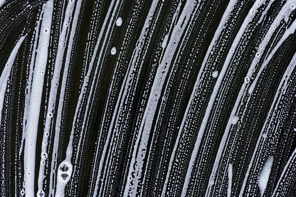 黒の表面に白い石鹸の泡 — ストック写真