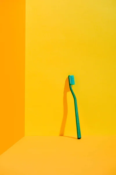 Зеленая Зубная Щетка Стоящая Оранжевой Стены — стоковое фото