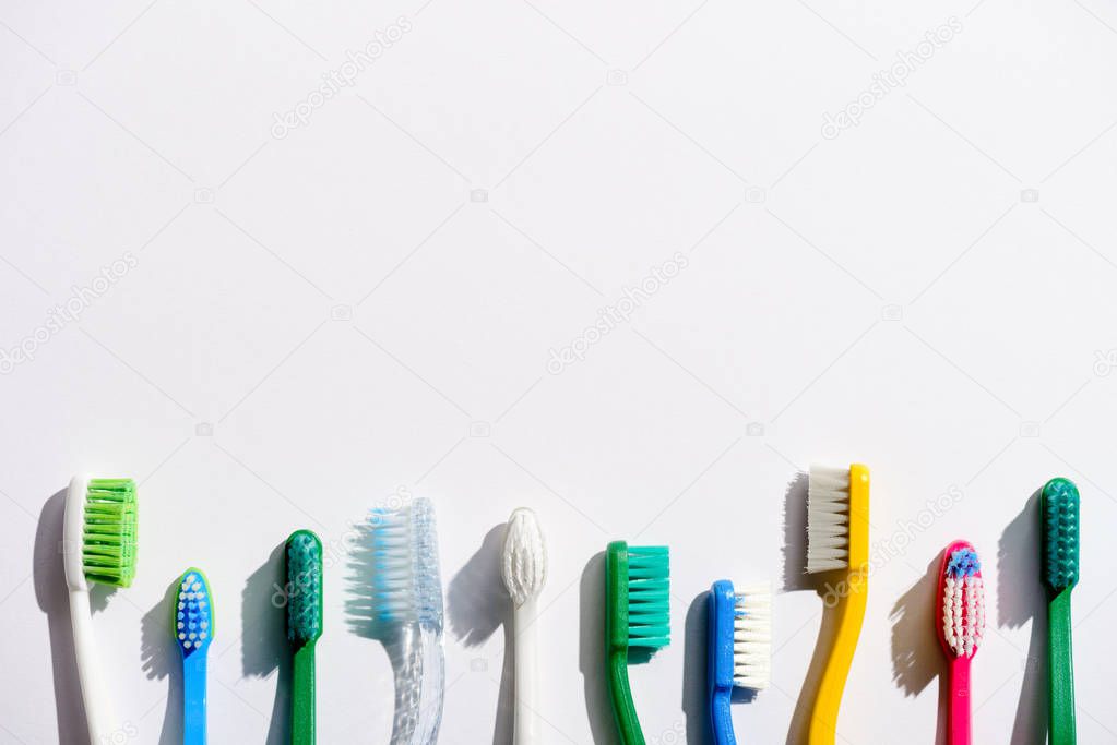 row of different toothbrushes, on white with copy space