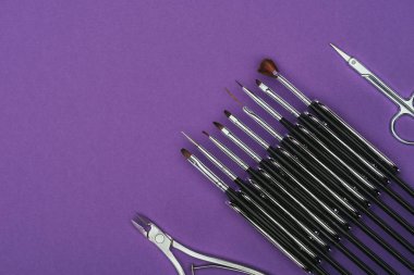 Fırçalar, makas ve mor üzerinde izole çivi kerpeten Üstten Görünüm