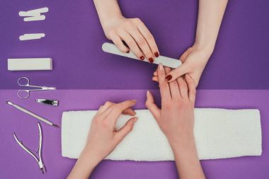 cropped image of manicurist filing nails with nail file clipart