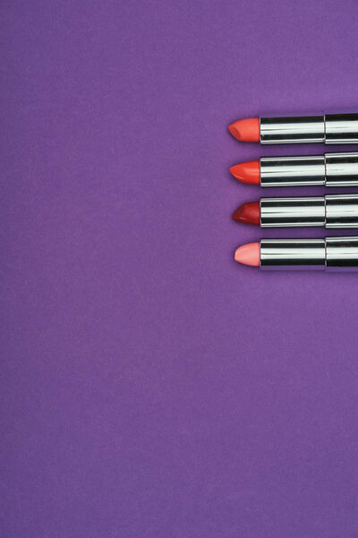 top view of red and pink lipsticks isolated on purple
