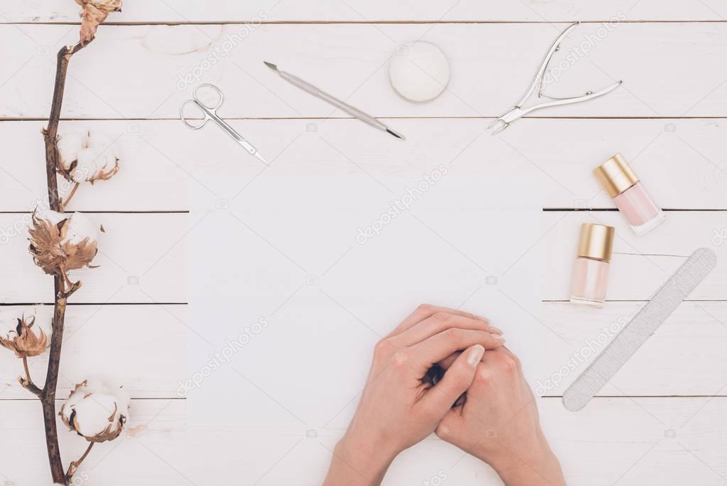 cropped image of woman sitting at table with manicure tools