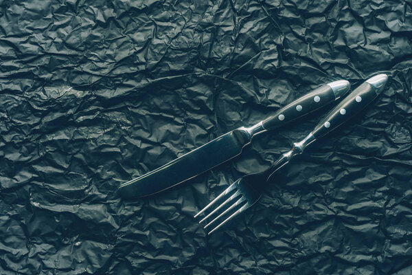 close up view steel fork and knife on dark textured surface