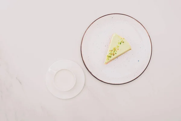 top view of piece of cake on plate and cup of milk on white surface